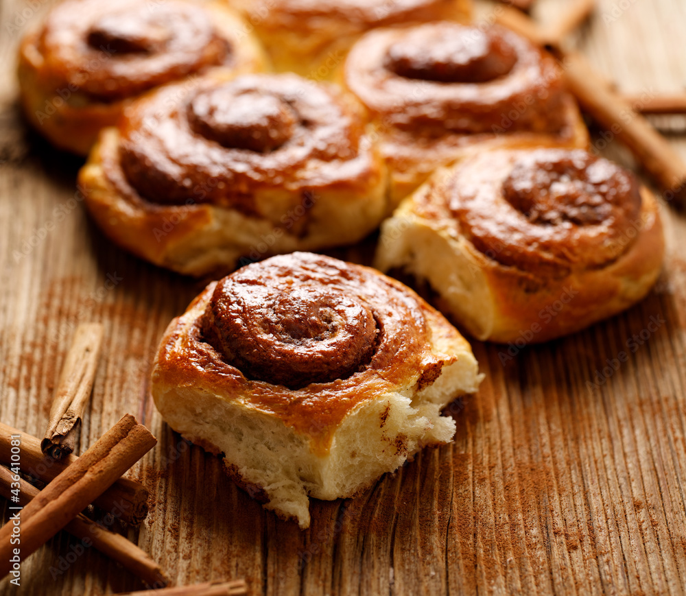Traditional spiral-shaped cinnamon buns on a wooden table, close up view