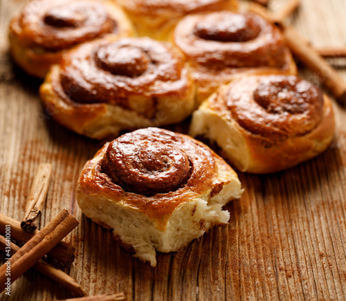 Traditional spiral-shaped cinnamon buns on a wooden table, close up view photo