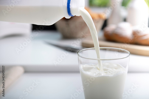 Pouring milk into glass in the kitchen.. photo