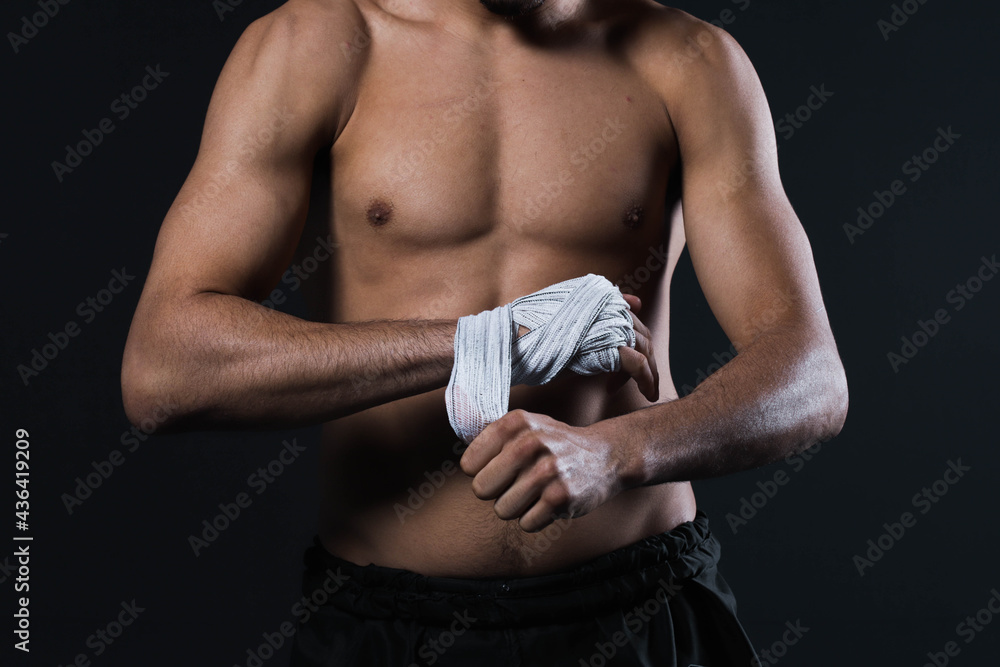 Naklejka premium Closeup male fighter hand with bandages. Fighter's fists clenched before a fight or training in a sports gym.