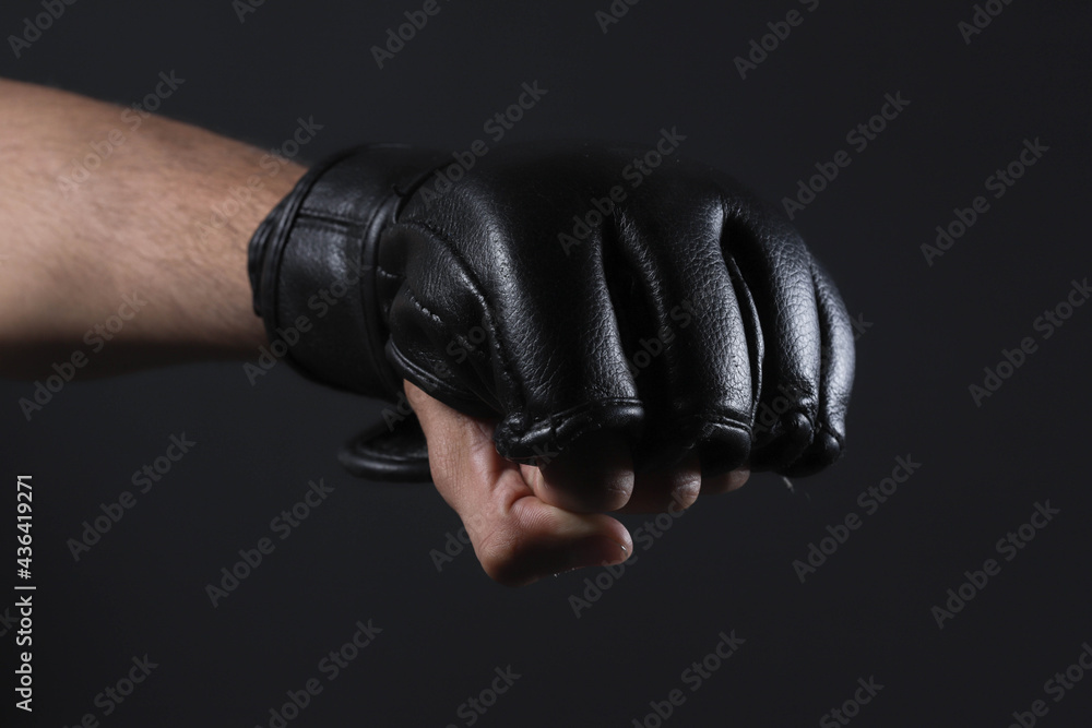Closeup male fighter hand with MMA glove. Fighter clenched fist before a fight or training in a sports gym.