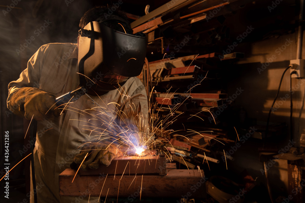 A welder is welding steel in an industrial factory. The welder wears protective clothing to work in the workplace. A welder is welding steel in an industrial factory. The welder wears protective clothing to work in the workplace.