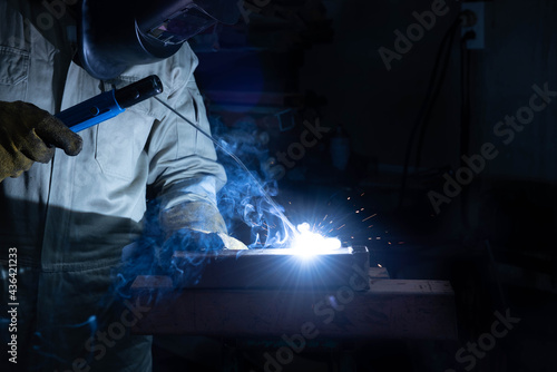 A welder is welding steel in an industrial factory. The welder w