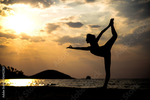 silhouette of a woman doing yoga on the beach