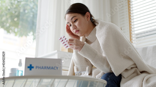Young asian woman receive check read medication capsule drug label package box free first aid kit from pharmacy hospital delivery service or drugstore at home in online telehealth telemedicine. photo