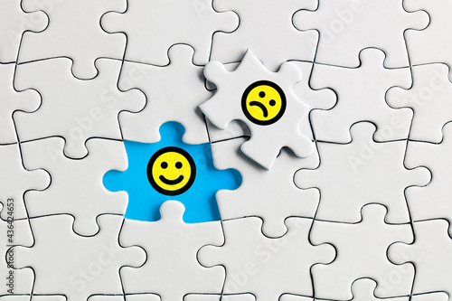 Happy smiling face exposed under the unhappy face icon on the missing puzzle piece. Customer satisfaction © Cagkan