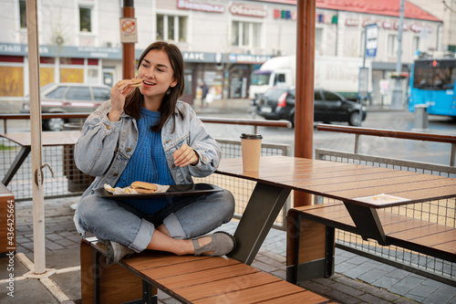 Street portrait of cheerful young woman eating fast food. Free Download Street portrait of cheerful young woman eating fast food. - GFXLoad