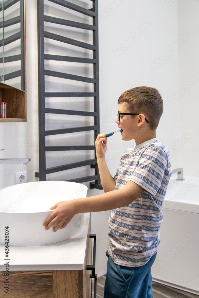 A little boy with glasses in the bathroom brushes his teeth. A little boy with glasses in the bathroom brushes his teeth.
