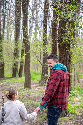 Little girl with dad is walking in the spring forest, holding hands. © puhimec