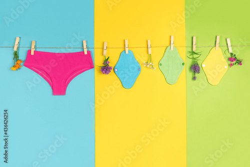 Panties and bamboo charcoal washable sanitary napkins on washing line. Healthy women's sanitary pads, reusable menstrual pads and natural flowers. Health care, zero-waste, eco-friendly concept