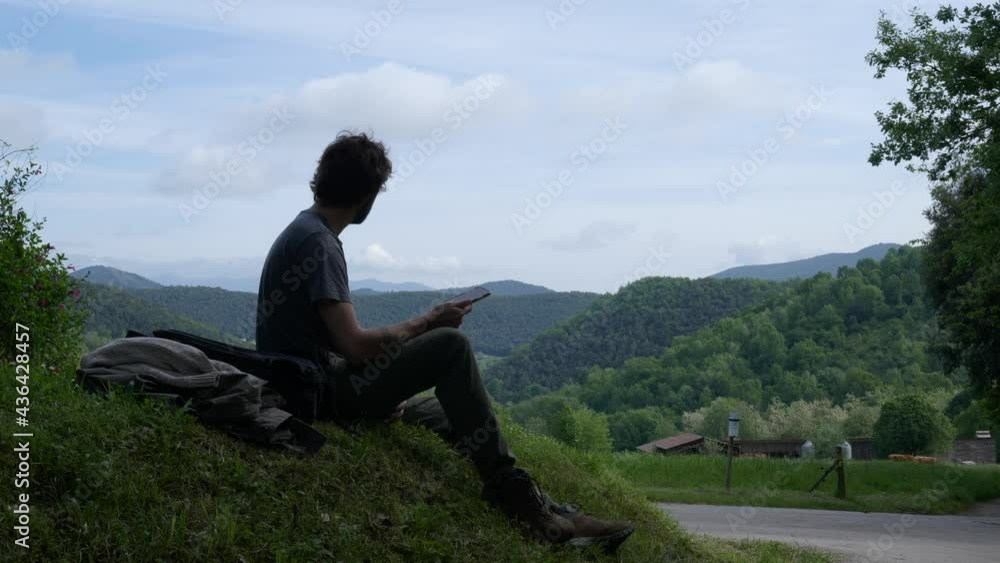 Silhouette of sad man sitting on rock in wilderness and getting bad news on mobile phone. Throwing away the phone. Silhouette of sad man sitting on rock in wilderness and getting bad news on mobile phone. Throwing away the phone.