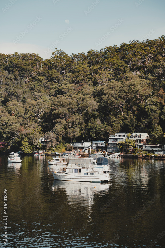 Boats on the water in front of idyllic waterfront houses at Berowra Waters NSW. As seen from the Great North Walk.