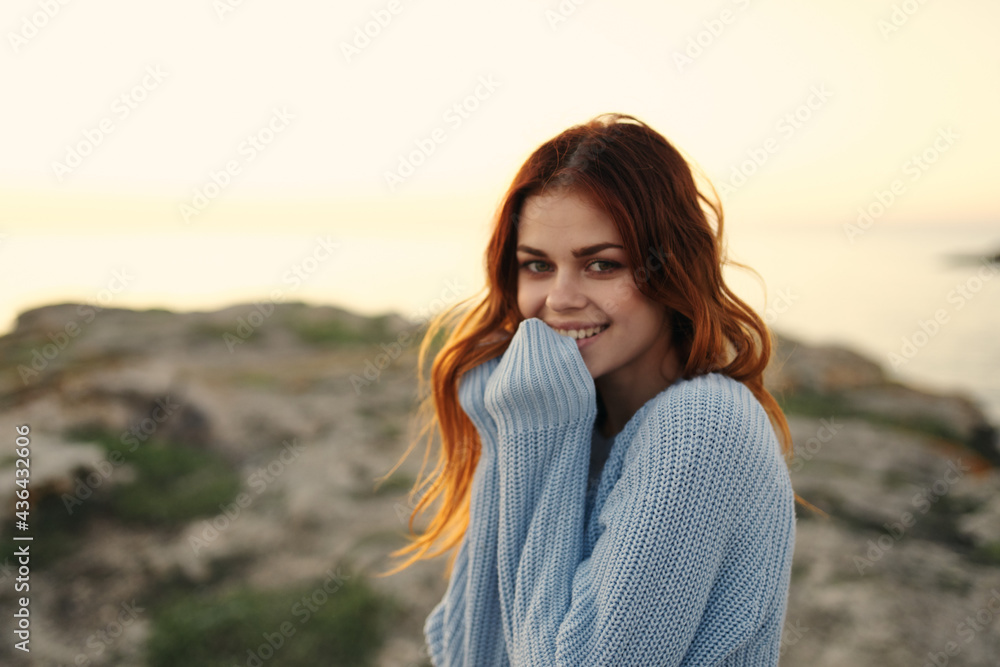 cheerful woman in a blue sweater outdoors sunset travel vacation