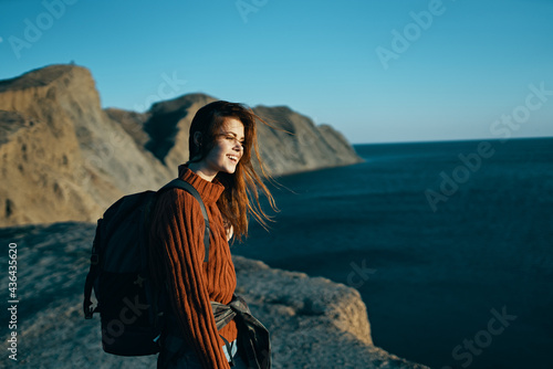 woman travels on nature in the mountains with a backpack near the sea