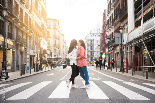 two girls kissing each other on the mouth in the middle of the road on the crosswalk in town © OMP.stock