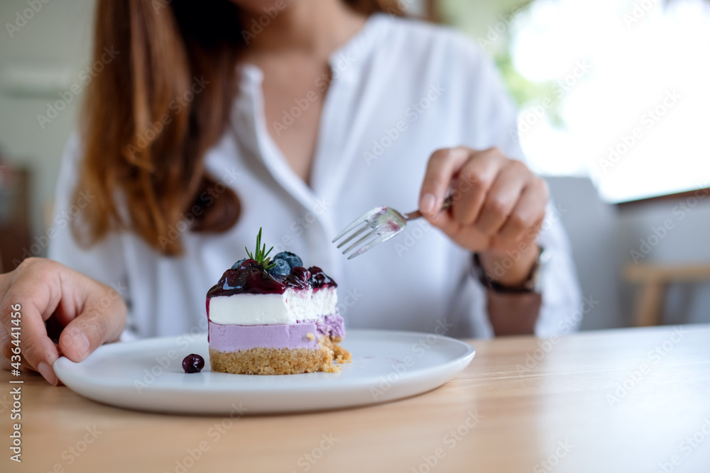 Closeup image of a woman eating a piece of blueberry cheesecake Closeup image of a woman eating a piece of blueberry cheesecake