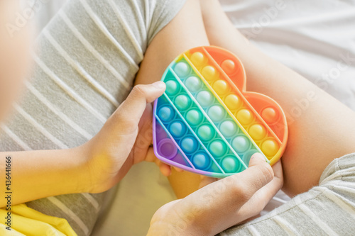 Colorful antistress sensory toy fidget push pop it in kid's hands.