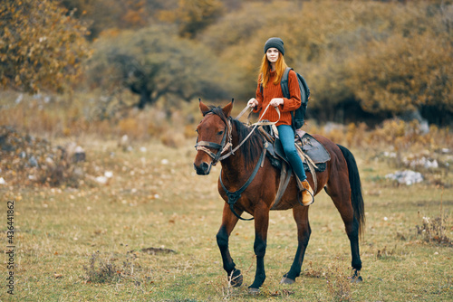woman hiker rides a horse in a field mountains nature landscape