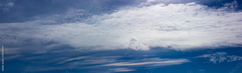 Blue sky with white clouds illuminated by the bright sun. Abstract blurred clouds in the sky float smoothly across the sky creating a beautiful summer landscape.