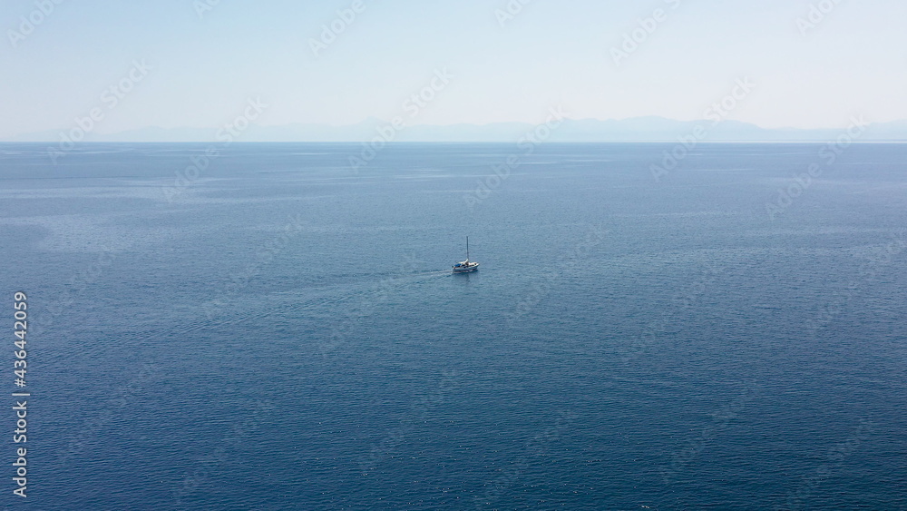 Incredible aerial shot in the open sea with a view of a white boat sailing in Aegean Sea, Greece. Incredible aerial shot in the open sea with a view of a white boat sailing in Aegean Sea, Greece.