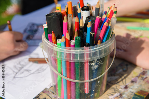 Colored pencils in a jar. Children draw on paper drawing class.