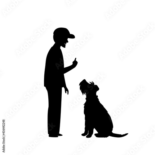 man teaching his dog basic obedience commant sit silhouette scene