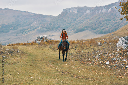 woman hiker in the mountains riding a horse adventure lifestyle