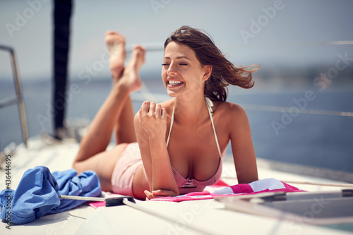 A young cheerful sexy model is relaxing and taking sunbath while enjoying a ride on a yacht. Summer, sea, vacation