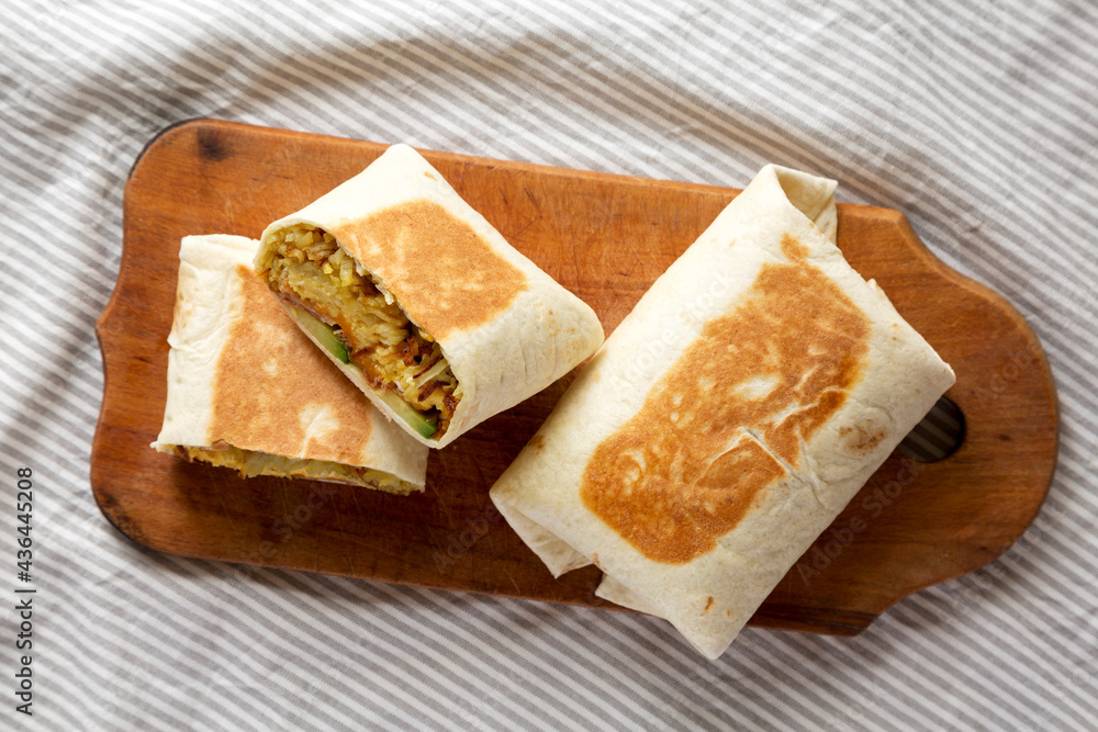 Homemade Breakfast Egg Burrito with Avocado and Bacon on a rustic wooden board, top view. Flat lay, overhead, from above. Homemade Breakfast Egg Burrito with Avocado and Bacon on a rustic wooden board, top view. Flat lay, overhead, from above.
