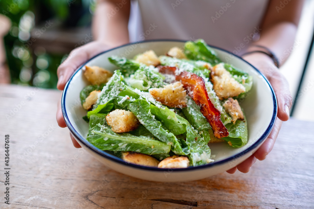 Closeup image of a woman holding a plate of Caesar salad Closeup image of a woman holding a plate of Caesar salad