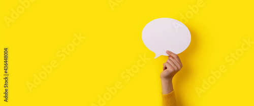 bubble speech layout in hand over yellow background, panoramic mock-up