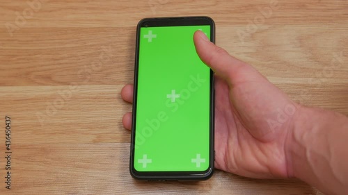 Mans hand with smartphone green screen thumb finger scrolls swipe