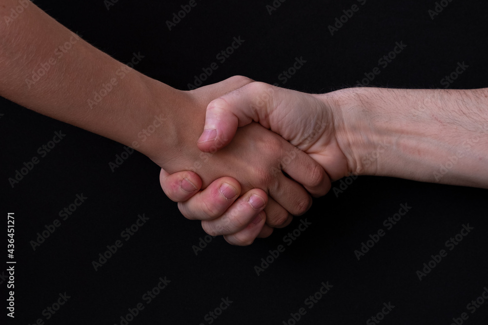 Close-up shot of two men shaking hands on a black background
