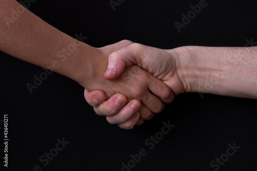 Close-up shot of two men shaking hands on a black background