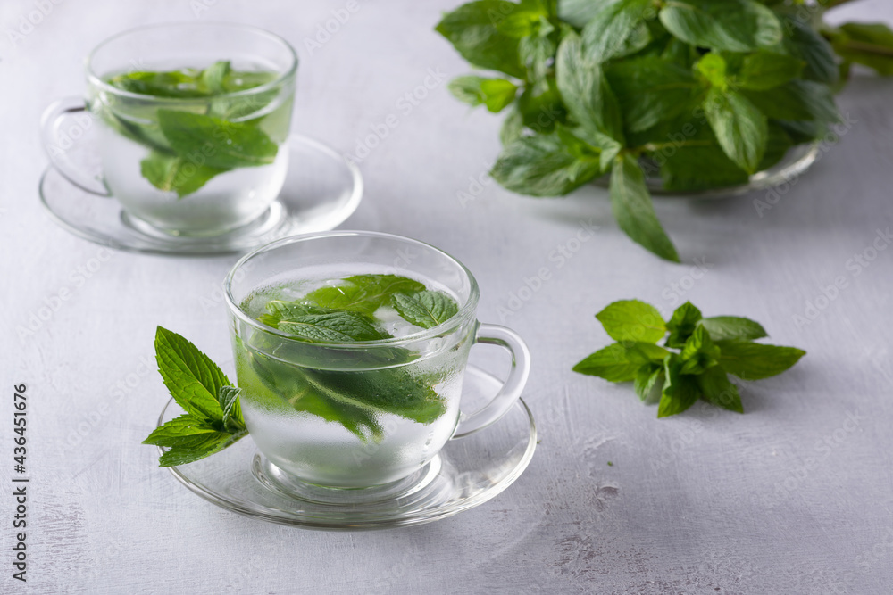 Iced mint tea, refreshing herbal drink in a glass with ice and fresh leaves on dark background Iced mint tea, refreshing herbal drink in a glass with ice and fresh leaves on dark background