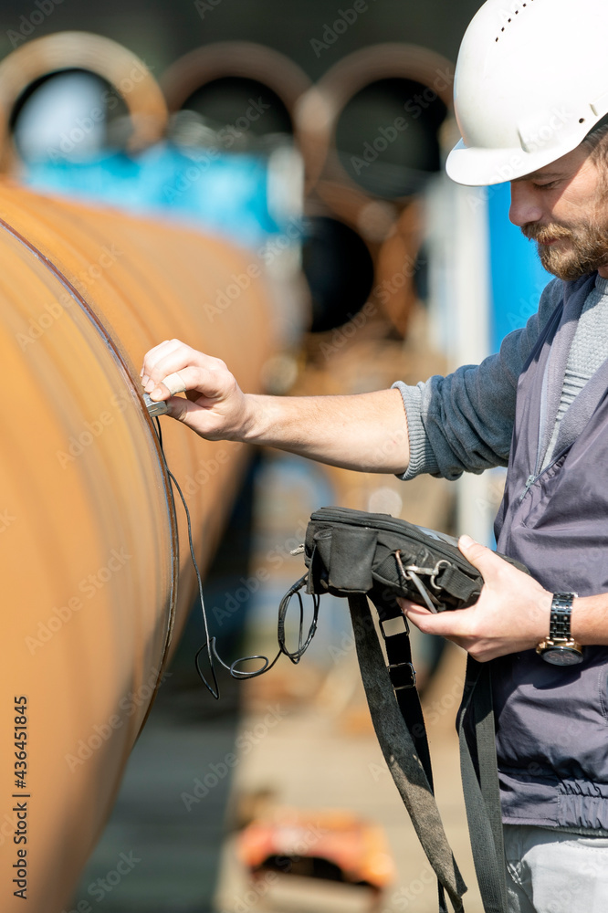 Obraz premium Technician is testing to welds of pipe with ultrasonic test method. It is a family of non-destructive testing techniques based on the propagation of ultrasonic waves in the object or material tested.
