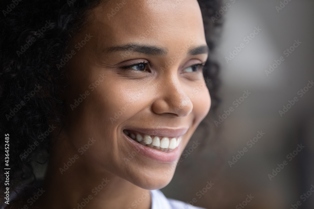 Close up side view of smiling young African American woman look in distance show white healthy teeth. Happy millennial biracial female think dream of opportunities perspectives. Diversity concept. Close up side view of smiling young African American woman look in distance show white healthy teeth. Happy millennial biracial female think dream of opportunities perspectives. Diversity concept.