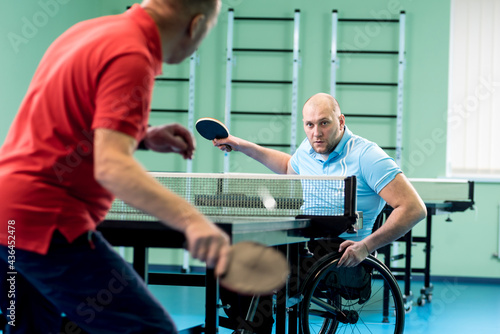 Print op canvas Adult disabled man in a wheelchair play at table tennis with his coach