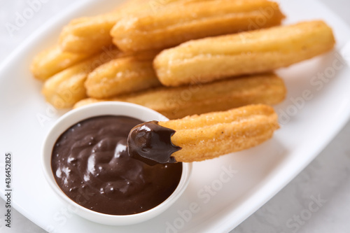 Churros with sugar and chocolate on a light background. Traditional Spanish fast food, homemade baking.