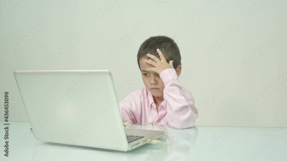 .A boy wearing a pink shirt was enjoying watching the laptop happily..Studio portrait, concept with white background. . .A boy wearing a pink shirt was enjoying watching the laptop happily..Studio portrait, concept with white background. .