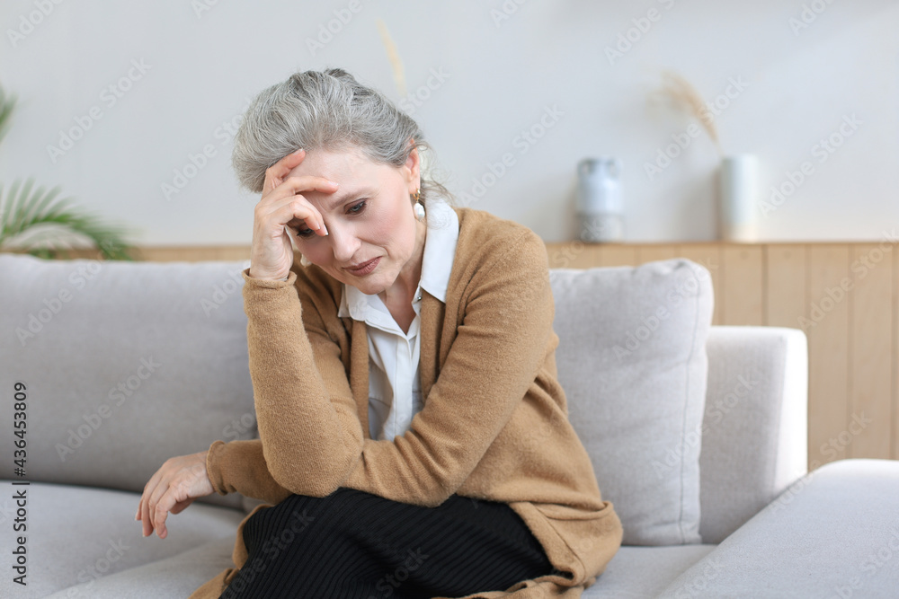 Worried middle aged woman sitting on a sofa in the living room. Worried middle aged woman sitting on a sofa in the living room.