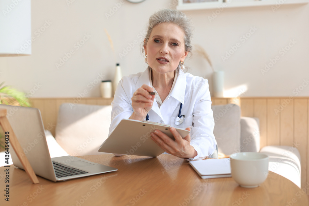 Older woman doctor therapist wearing headset video call talking to web camera consulting virtual patient online by video conference call chat. Older woman doctor therapist wearing headset video call talking to web camera consulting virtual patient online by video conference call chat.