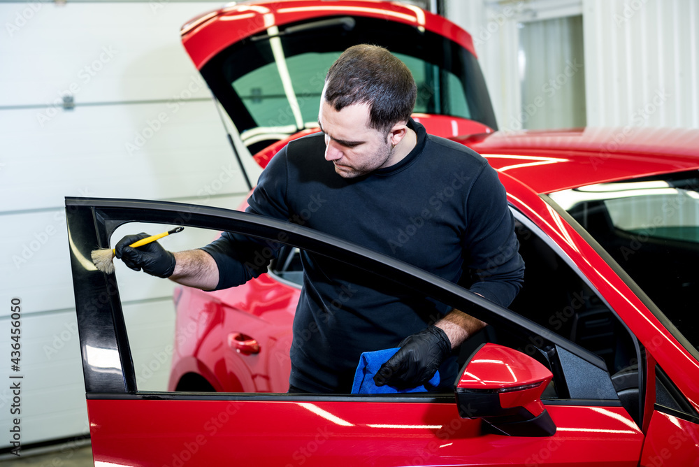 Car service worker cleans interiror with special brush Car service worker cleans interiror with special brush