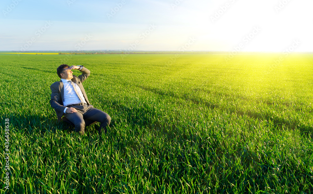 businessman sits in an office chair in a field and rests, freelance and business concept, green grass and blue sky as background businessman sits in an office chair in a field and rests, freelance and business concept, green grass and blue sky as background
