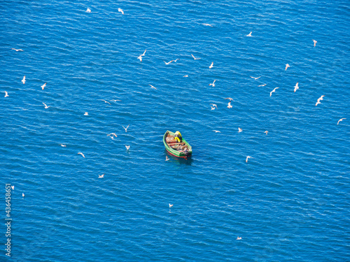 A lone boat with industrial fishermen in the open sea with a rod and nets. The concept of poaching and illegal fishing.