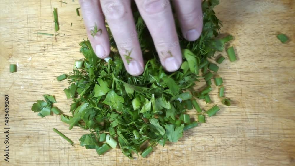 Hand touches chopped green dill and parsley in slow motion. Hand touches chopped green dill and parsley in slow motion.