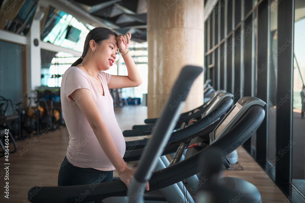 Pregnant Asian woman exercising in the gym indoors for a fit and active pregnancy Pregnant Asian woman exercising in the gym indoors for a fit and active pregnancy