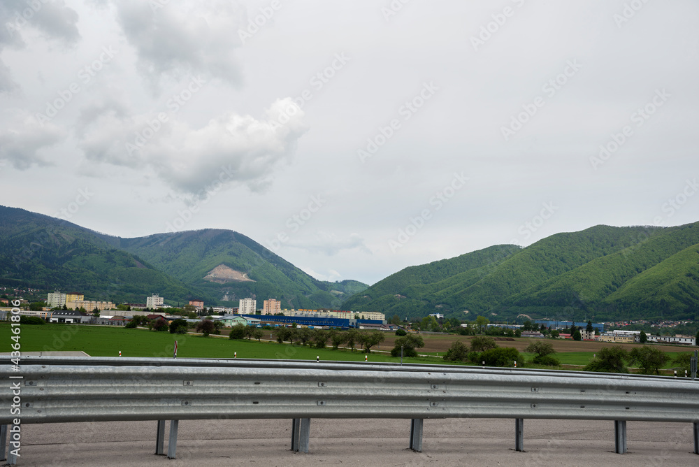 Fototapeta premium Highway fence in the mountain landscape. Village with houses and buildings