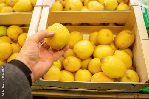 man hands taking lemon in groceries store