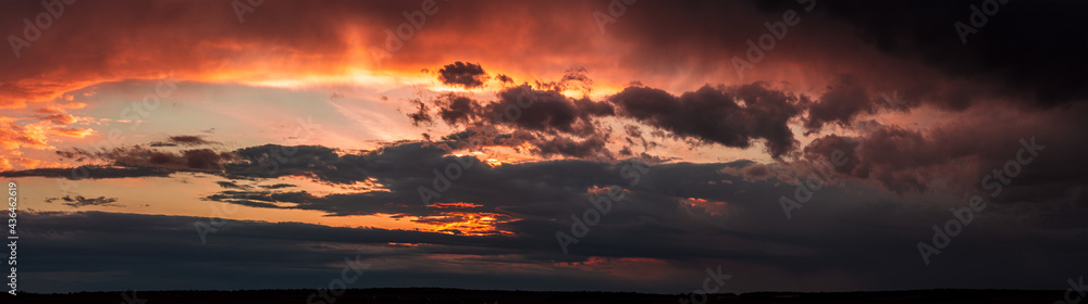 Fototapeta premium Dramatic dark sunset. Panorama of dark rain clouds in the evening. A rich red sky before a night thunderstorm